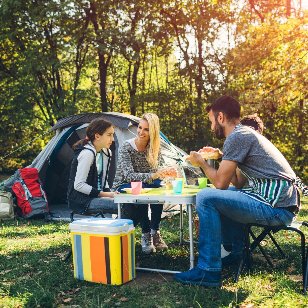Family of four enjoying a picnic near a tent in a forest