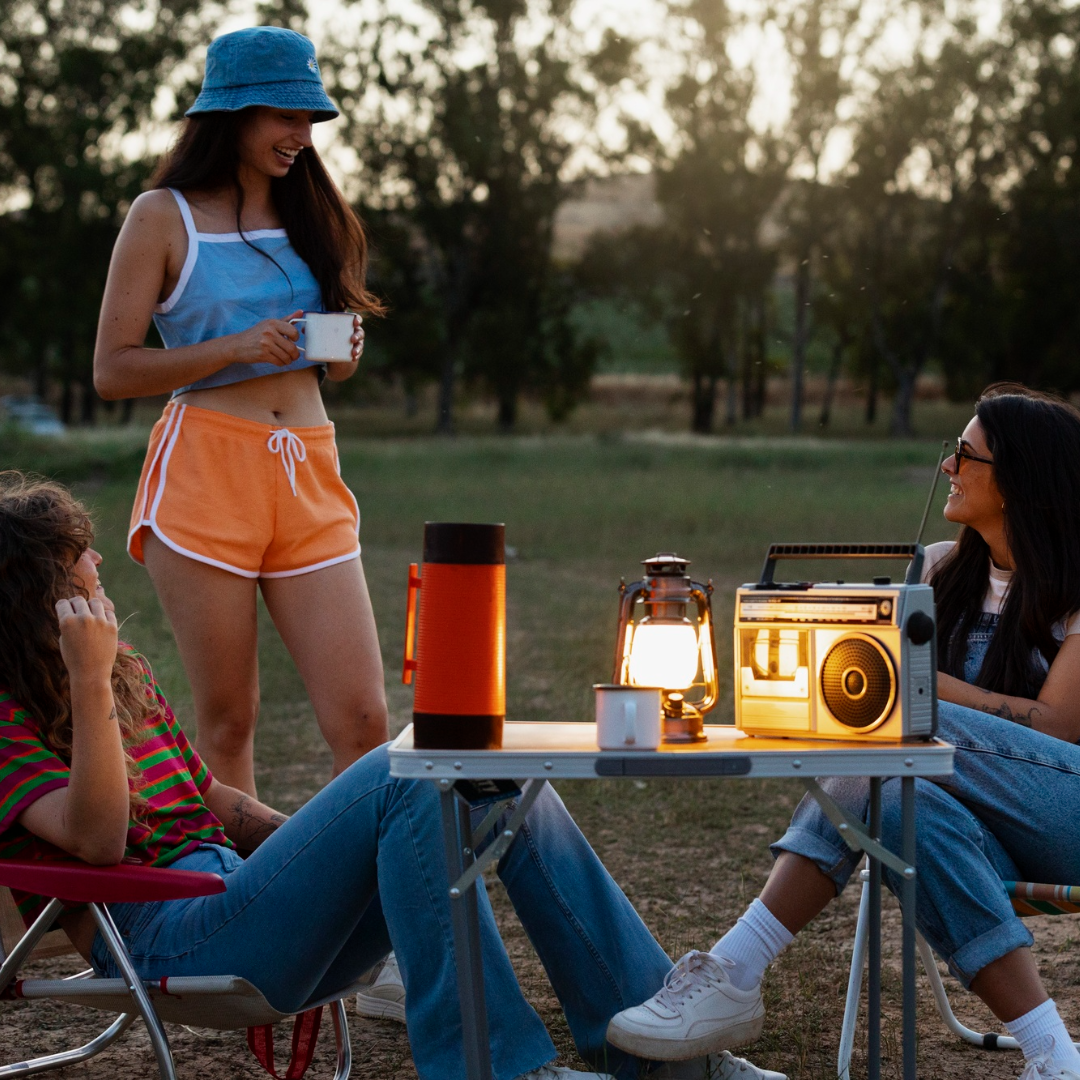 People enjoying a camping trip with a radio and lantern in a park setting.