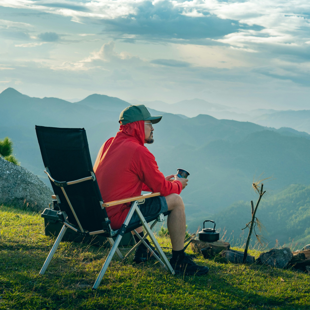 Person in a red jacket sitting in a chair with a scenic mountain view